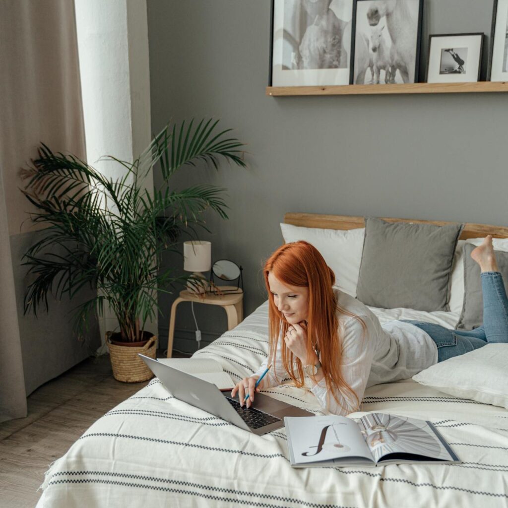 Girl lying on bed watching trending news on laptop